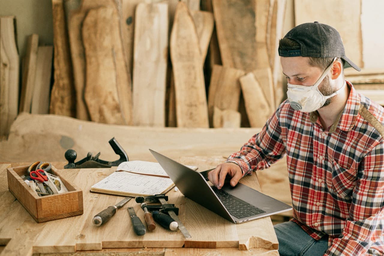 Contractor on construction job sitting down looking at his laptop in front of his tools